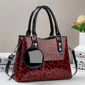 Détail du sac à main en cuir verni léopard rouge et noir avec un petit porte-monnaie assorti