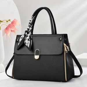Detail of black woven texture handbag with golden hardware and houndstooth silk scarf