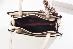Top view of beige tote bag interior showing three compartments and silk scarf detail