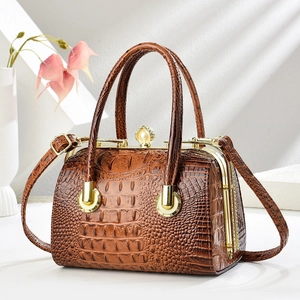Detail of brown crocodile pattern handbag with pearl clasp and golden metal frame