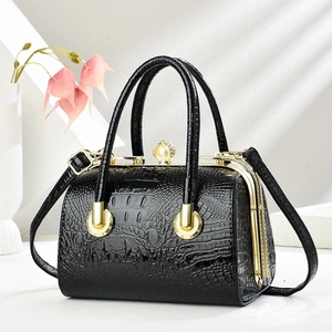 Detail of black crocodile texture handbag with gold metal frame and pearl clasp closure