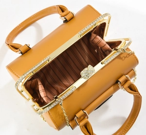 Detail view of caramel brown evening bag with crystal bow clasp and striped lining
