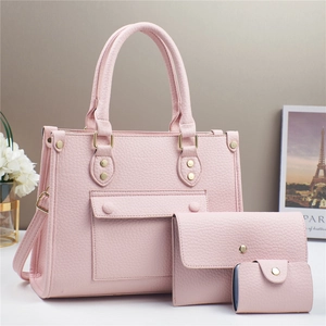 Detail of pink three-piece bag set with litchi grain texture and gold hardware