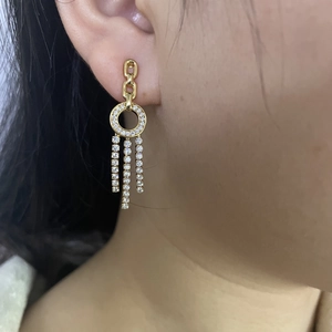 Macro shot of long gold tassel earrings with rhinestone rings on a model