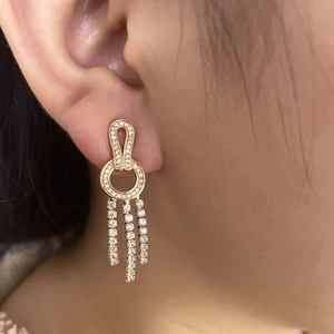 Detailed view of long gold tassel earrings with shimmering white cubic zirconia stones