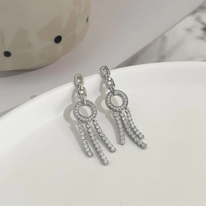 Close-up of silver tassel earrings with white zircon on a white ceramic plate edge