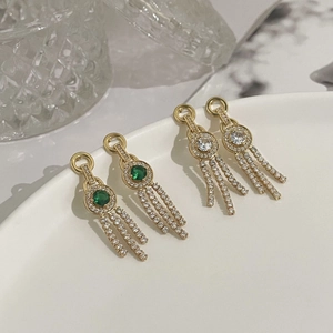 Exquisite gold tassel earrings with emerald and zircon stones shown in a luxury setting