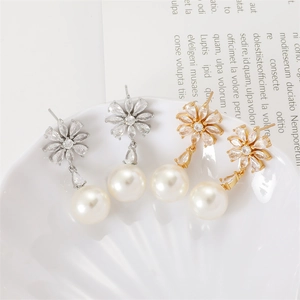 Daisy flower pearl earrings in gold and silver finish displayed on a white shell