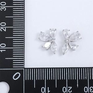 Macro view of leaf-shaped silver stud earrings with zircon stones and scale measurement