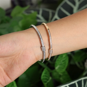 Détails de joncs en argent et or rose sertis de zircons portés sur un poignet