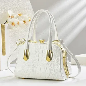 Detail of white crocodile texture evening bag with crystal clasp and gold metal frame