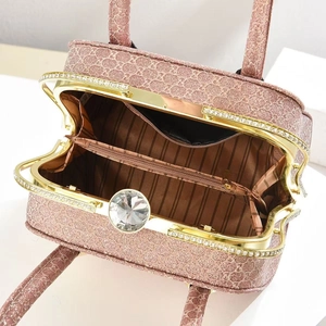 Detail view of the pink evening bag featuring a crystal clasp and striped interior lining