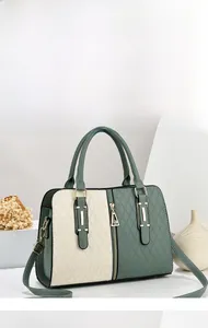 Detail of sage green and beige quilted handbag with gold hardware and reinforced handle