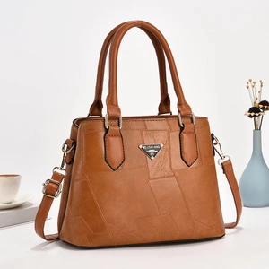 Detailed view of brown bucket bag with geometric leather patchwork and silver brand plate