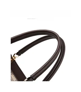 Detailed shot of dark brown leather arched handle with neat stitching on a vintage handbag