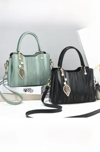 Detail of wave-textured handbags in green and black with metal leaf and pearl pendants