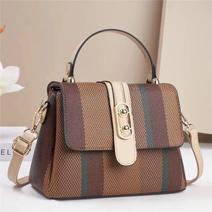 Vintage striped woven handbag with leather handles and adjustable strap on a neutral background
