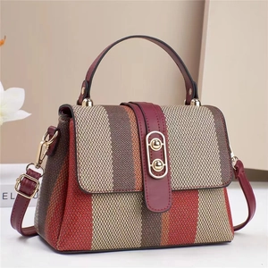 Detail of woven fabric texture with burgundy leather strap and golden capsule clasp lock