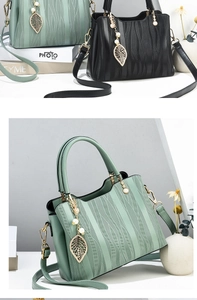 Detailed view of wave-textured leather handbag with golden leaf and pearl charm