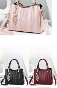 Detail of elegant wavy-textured handbags in pink, black and burgundy with leaf charms