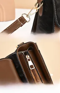 Detail of light gold hardware clasp and zipper on black pebbled leather handbag