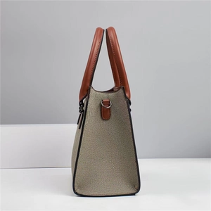 Detail view of the beige woven fabric and brown leather side panel of this tote bag