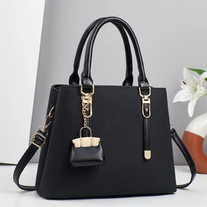 Borsa a mano nera a righe con dettagli dorati e mini ciondolo in esposizione studio