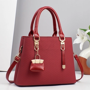 Borsa a mano bordeaux a righe con dettagli dorati e mini ciondolo decorativo