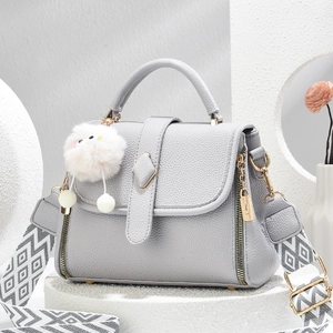 Sac à main en cuir litchi gris clair avec bandoulière géométrique sur socle blanc