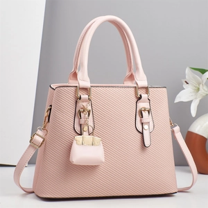Detail of light pink tote bag with textured stripe pattern and mini bag charm accessory