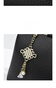 Detail of gold Chinese knot pendant with pearls on black lychee grain leather tote bag