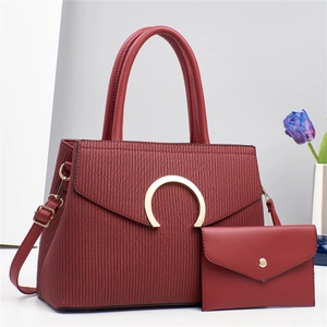 Macro detail of wine red PU leather texture and gold horseshoe clasp on shoulder bag