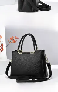 Detail view of black lychee grain leather tote bag with gold metal hardware accents