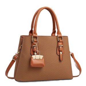 Brown woven tote bag with smooth leather handles and a mini coin purse charm decoration
