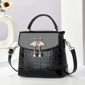 Mini sac noir gaufré crocodile avec fermoir cygne en cœur doré et pompon en perles