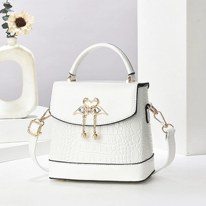 Détail du sac blanc à motif crocodile avec fermoir cygne coeur et pendentif perle