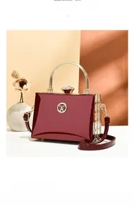 Detail of burgundy patent leather evening bag with golden handle and crystal clasp