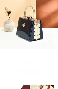 Detail of glossy patent leather clutch with multi-layer plated gold handles and accents
