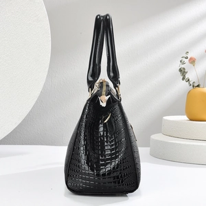 Detail of black faux crocodile patent leather tote with premium gold hardware accents