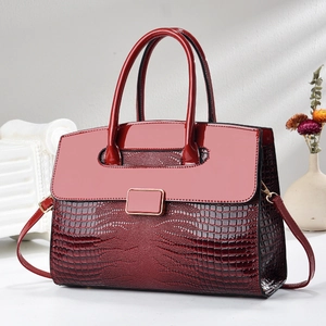 Détail du sac à main rouge en cuir verni à motif crocodile avec boucle dorée sur support