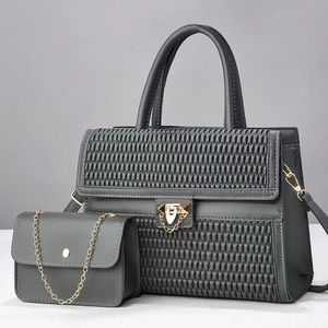 Detail of gray quilted tote bag set with golden metal locks and chain strap
