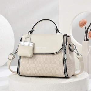 Detail of cream white leather and fabric handbag with mini pouch on a stone pedestal