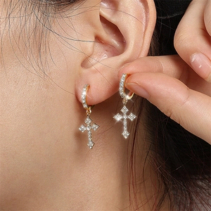 Boucles d'oreilles créoles croix dorées avec zircons blancs portées par un mannequin