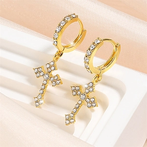 Détail de boucles d'oreilles créoles dorées avec pendentifs croix et oxydes de zirconium