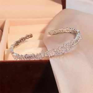 Elegant silver open bangle with geometric rectangular zircons on silk background