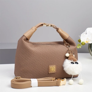 Detail of brown woven handbag with cute plush charm and detachable leather strap