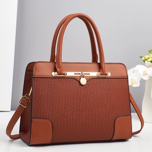 Detail of caramel brown tote bag with striped texture, gold padlock, and dual handles