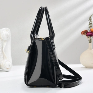 Detail view of glossy black faux-crocodile leather handbag with gold metal hardware