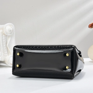 Detailed base view of black crocodile pattern bag with four protective gold metal feet