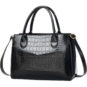Macro shot of black glossy crocodile pattern leather and golden hardware on business bag